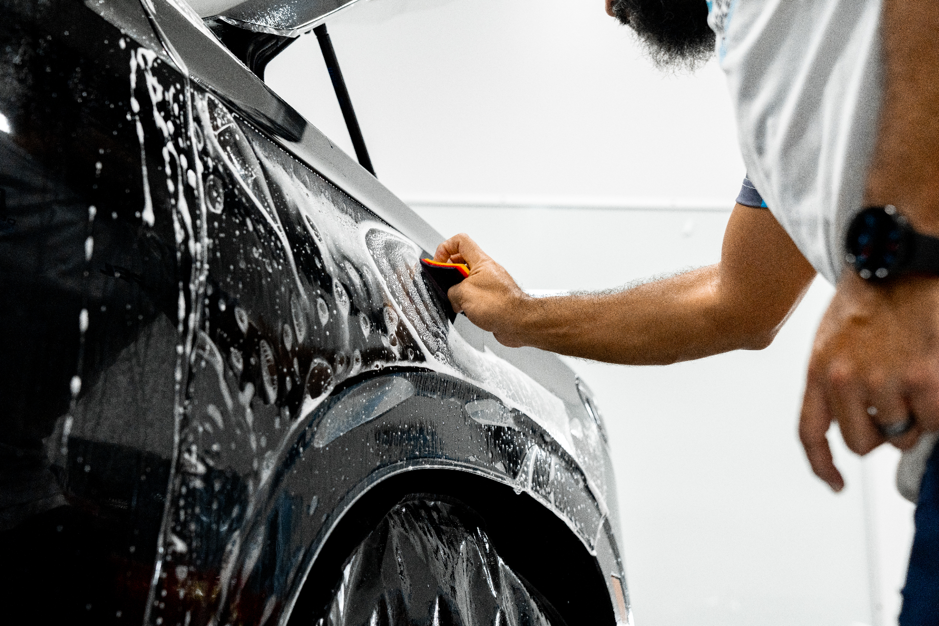 XPEL certified installer squeegeeing paint protection film on a deep blue sports car door
