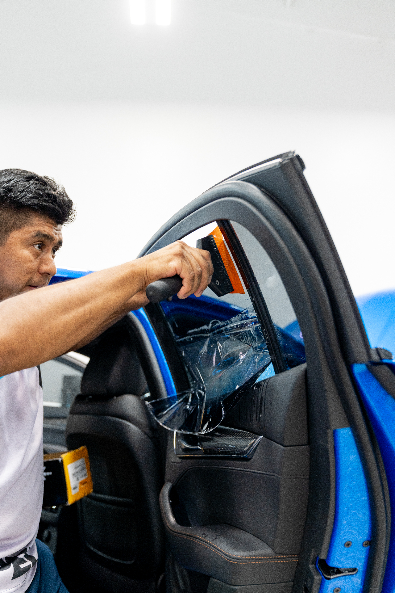Installer applying XPEL ceramic window tint to a rear windshield from inside the vehicle
